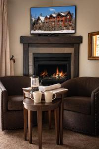 a living room with a fireplace with a tv above it at A Bear and Bison Country Inn in Canmore