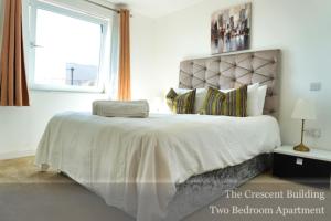 a bedroom with a large white bed with a large window at Gunwharf Quays Apartments in Portsmouth