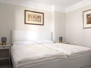 białe łóżko w sypialni z dwoma zdjęciami na ścianie w obiekcie Cabeho Beach Homes w mieście Calpe