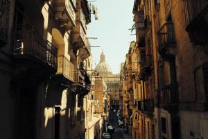 a view of an alley between buildings with a dome at 19 ROOMS in Valletta