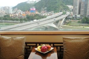 a plate of fruit on a table with a bridge at Beautiful Hotel Taipei in Xindian
