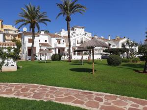 ein Park mit Palmen und Sonnenschirmen auf einem Rasen in der Unterkunft Mare Nostrum II Denia. in Denia