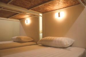 ein Schlafzimmer mit 2 Betten mit Kissen darauf in der Unterkunft ATOM Poshtel in Mae Sariang