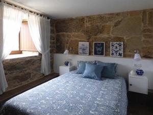 1 dormitorio con cama y pared de piedra en CASA VEIGA, en Pontevedra