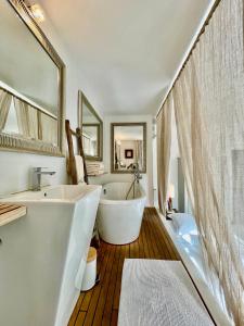 een witte badkamer met een bad en een wastafel bij Maison De Mon Père in Aigues-Mortes