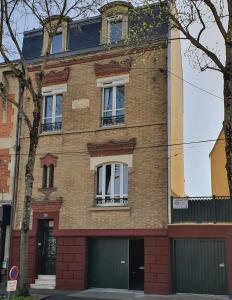 un bâtiment en briques avec deux fenêtres et un garage dans l'établissement Libération-Maison d'hotes, au Mans