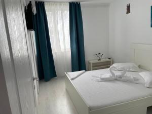 a bedroom with a white bed with a blue curtain at Apartament Olimp in Olimp