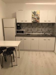 a kitchen with white cabinets and a table and chairs at Apartament Olimp in Olimp