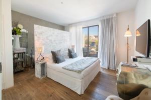 a bedroom with a white bed and a large window at Maison De Mon Père in Aigues-Mortes