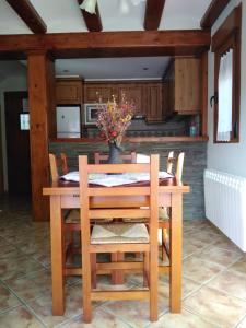 una mesa de madera con sillas y un jarrón con flores en Casa La Bordeta Remondillo, en San Juan de Plan