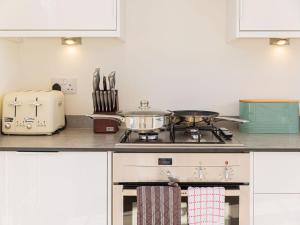 
a kitchen with a stove top oven and a microwave at 10 Tivoli Mews - By Luxury Apartments in Cheltenham
