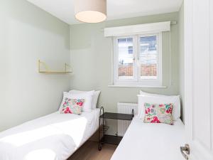 10 Tivoli Mews - By Luxury Apartments في تشلتنهام: سريرين في غرفة صغيرة مع نافذة