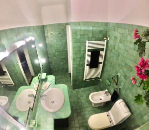 a green tiled bathroom with two sinks and a mirror at Casa del Ginnasio - Taormina city center in Taormina