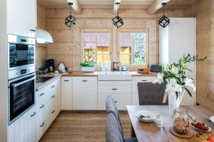 a kitchen with white cabinets and a wooden wall at Willa Pitoniówka z sauną, Netflix oraz Xbox one in Kościelisko