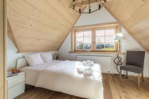 a bedroom with a white bed and a chair at Willa Pitoniówka z sauną, Netflix oraz Xbox one in Kościelisko