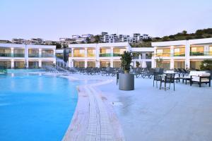 a swimming pool with chairs and tables and buildings at Jasmin Elite Residence & SPA in Gümbet