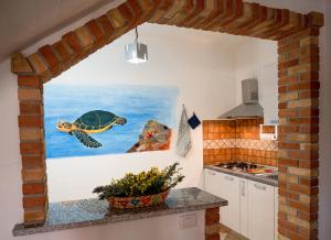 a kitchen with a painting of a turtle on the wall at Il Veliero Tanca Piras in Nebida