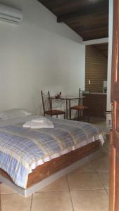 a bed in a room with a table and chairs at Vilarejo Penedo Chalés in Penedo