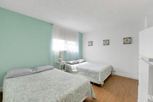 ハリウッドにある2 BEDROOMS 2 FULL BATHROOMS APT. ON THE BEACHの緑の壁と窓が特徴の客室で、ベッド2台が備わります。