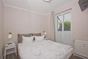 ein weißes Schlafzimmer mit einem weißen Bett und einem Fenster in der Unterkunft zentrale FeWo mit Balkon, gratis Nutzung vom AHOI Erlebnisbad und Sauna in Sellin - Villa Buskam FeWo 22 in Göhren + 14 Fotos