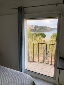 a bedroom with a large window with a view of the ocean at Hotel Les Pecheurs in Banyuls-sur-Mer
