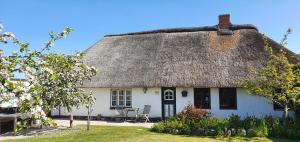 a thatch roofed cottage with a table and chairs at Haus-an-de-Marsch in Midlum