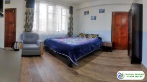 a bedroom with a bed and a chair and a window at MANNA INSPIRA in Shillong