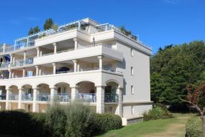 a large white building with balconies and trees at Appartement de standing avec Piscine in La Baule