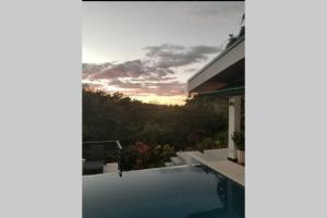 諾薩拉的住宿－New Hill top Home with a Beautiful Tropical View，一座带游泳池的别墅,享有日落美景