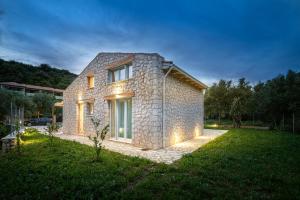 a stone house in a yard with lights on it at Angello Villas in Agios Nikitas