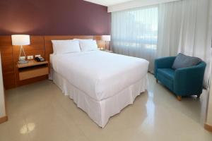 a bedroom with a large white bed and a blue chair at Staybridge Suites Guadalajara Expo, an IHG Hotel in Guadalajara