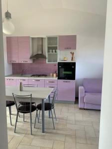 サンタンナ・アッレージにあるOrchidea Porto Pinoのキッチン(紫色のキャビネット、テーブル、椅子付)