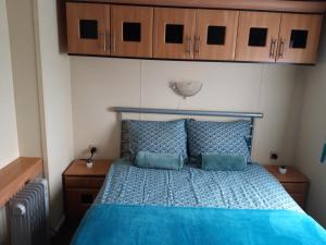 um quarto com uma cama azul e armários de madeira em Locatie Het Knooppunt Engelse Chalet em Nuis