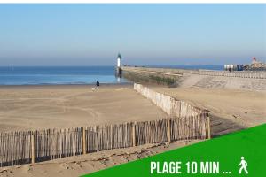 a person walking a dog on a beach with a lighthouse at Joli petit studio près du phare in Calais +8 photos