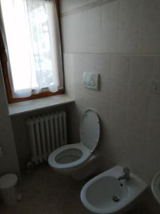 a bathroom with a toilet and a sink and a window at AJARNOLA N14 in Padola