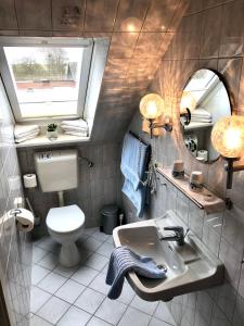 uma casa de banho com um lavatório, um WC e um espelho. em Haus Magnussen em Dagebüll