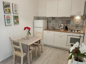 una cucina con tavolo e sedie e una cucina con armadietti bianchi di Botteghelle Home a Casalnuovo di Napoli