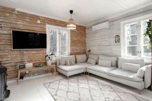 sala de estar con sofá y TV en Beautifully renovated lakeside red cottage, en Salo