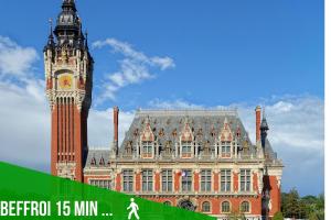 a large building with a clock tower and a building with a clock at Studio éco proche du phare in Calais