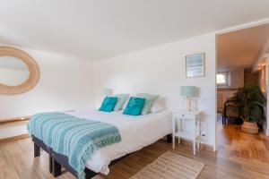 sypialnia z białym łóżkiem z niebieskimi poduszkami w obiekcie SUITE Souplex Château Côte de Nacre w mieście Ver-sur-Mer
