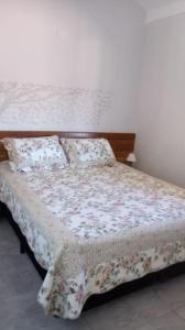 a bedroom with a bed with a floral bedspread and pillows at Chale do Caruso in Mairinque