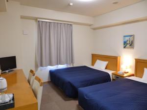Habitación de hotel con 2 camas, escritorio y TV. en Smile Hotel Shizuoka Yoshida Inter, en Yoshida