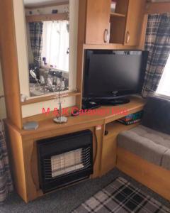 a living room with a tv and a fireplace at Beautiful 6 birth caravan in Ingoldmells