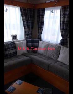 a couch in a living room with two windows at Beautiful 6 birth caravan in Ingoldmells