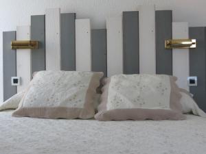 a bed with two pillows on top of it at Le Parasol in Ars-en-Ré