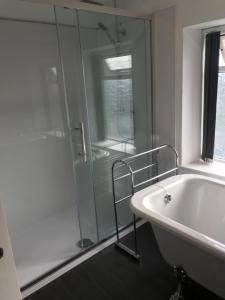 a white bathroom with a tub and a shower at Heulwen in Barmouth +23 photos