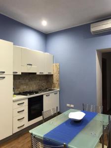 a kitchen with white cabinets and a blue wall at Civico 78 in Montefiascone