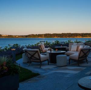 a patio with chairs and tables next to a body of water at Wequassett Resort and Golf Club in East Harwich