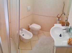 bagno bianco con servizi igienici e lavandino di Suites Pratoranieri Beach a Follonica