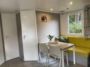 ein Wohnzimmer mit einem Tisch, Stühlen und einem Fenster in der Unterkunft Neat chalet with microwave Antwerp at 39 km in Rijkevorsel